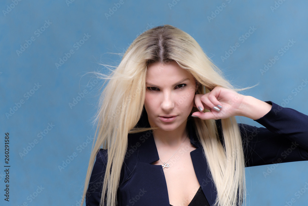 Naklejka premium Portrait of happy smiling young cheerful businesswoman standing with flowing hair. Success in business concept studio shot. Blue suit.