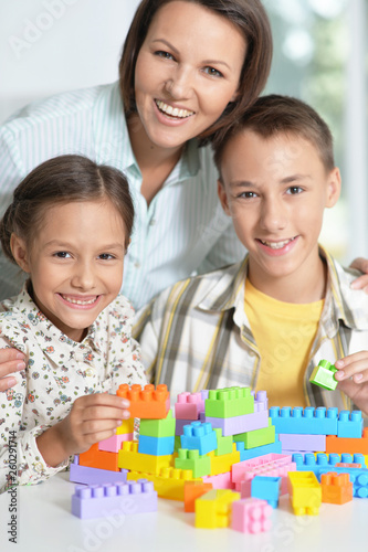 Mother and children playing with colorful plastic blocks