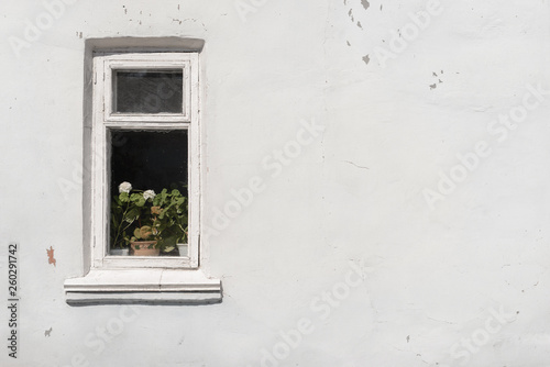 A small window in an old shabby white wall