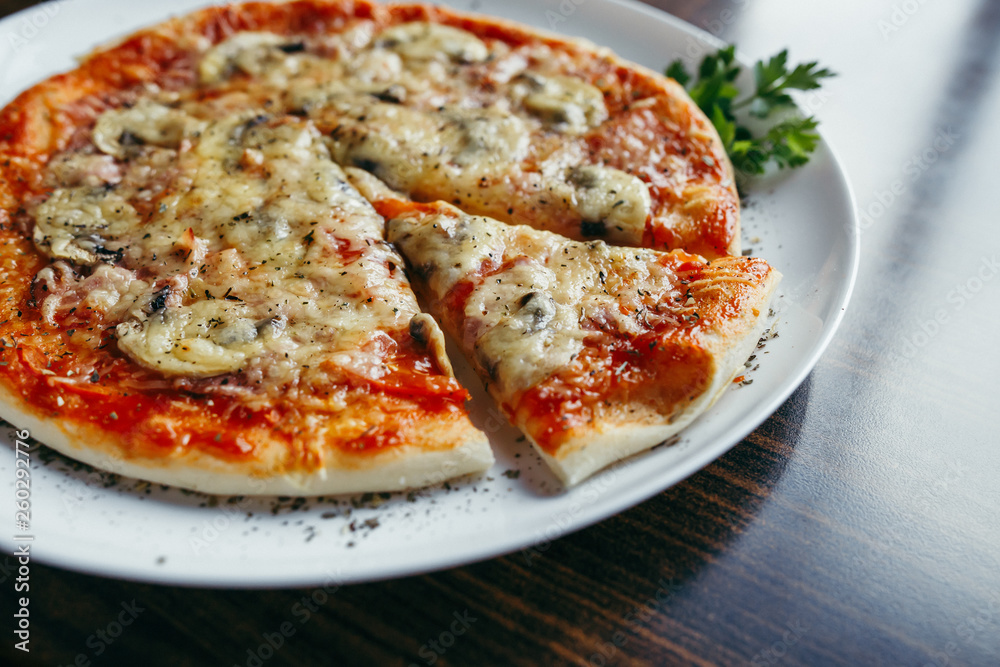 Hot pizza slice with melting cheese on a wooden table. Hot pizza slice with melting cheese on a wooden table.