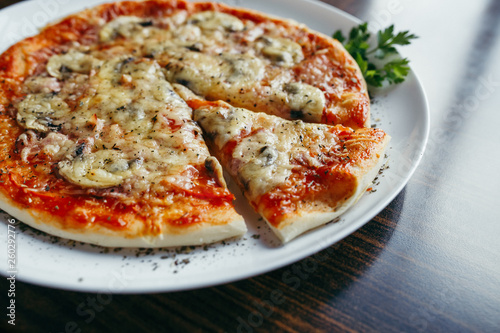 Hot pizza slice with melting cheese on a wooden table.