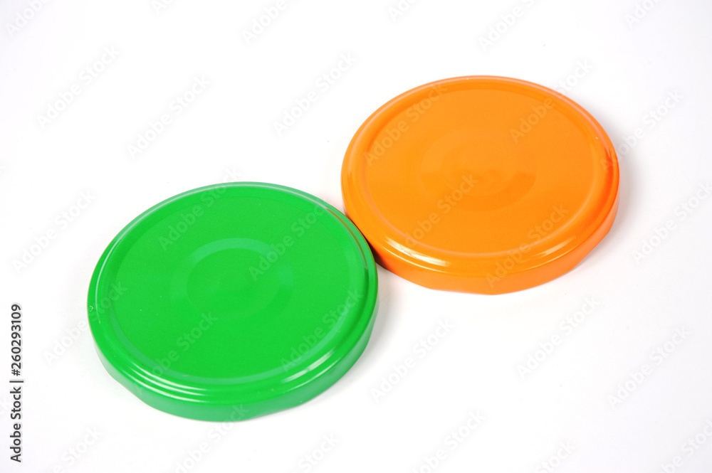 Screw caps for glass jars. For canning, canned food. Orange, green caps on white background Screw caps for glass jars. For canning, canned food. Orange, green caps on white background