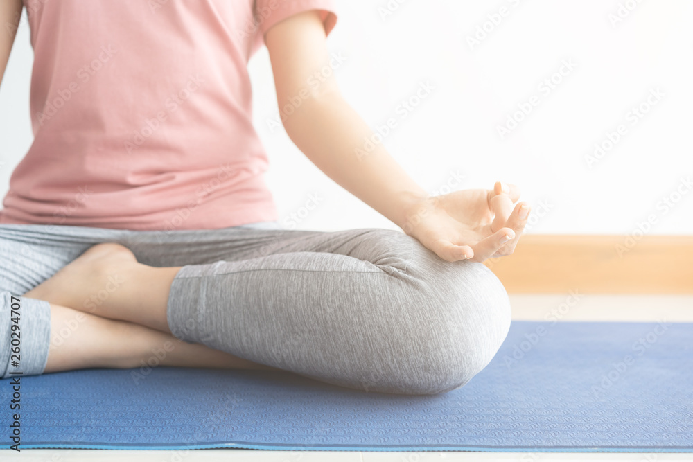 Close up hand and half body of healthy woman sit in lotus Yoga position.Young healthy woman sitting posture exercise in home.Concept of meditating,lifestyle and relaxation.