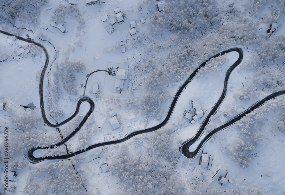 Aerial view of road in winter landscape.  Village and forest view from above with a drone.