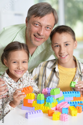 Portrait of father and children playing with colorful plastic bl