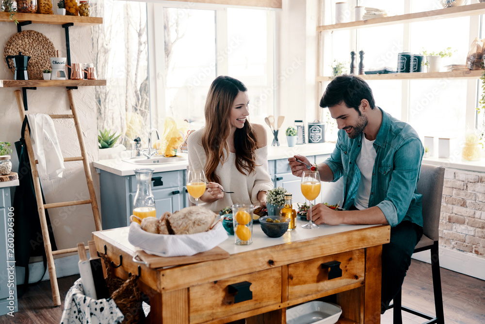 Perfect breakfast. Beautiful young couple enjoying healthy breakfast while sitting in the kitchen at home