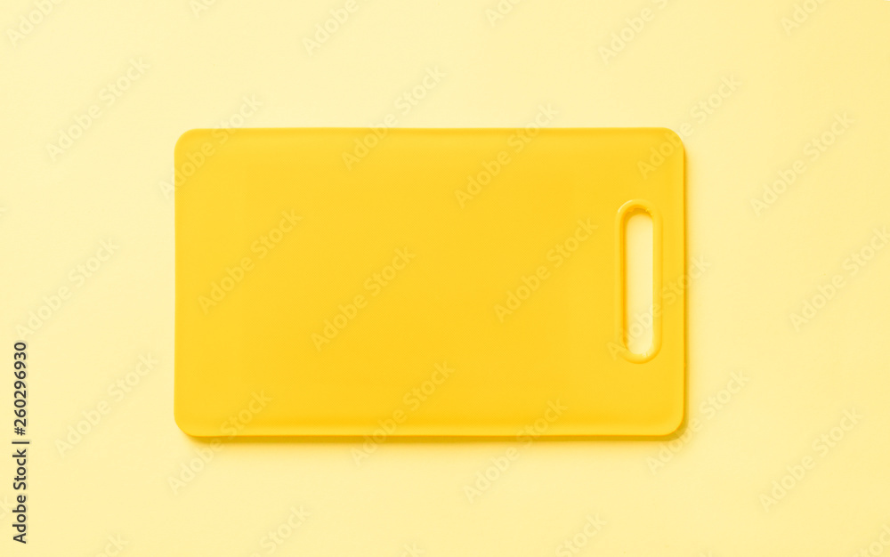 Colored yellow plastic cutting board on yellow background, top view. Colored yellow plastic cutting board on yellow background, top view.