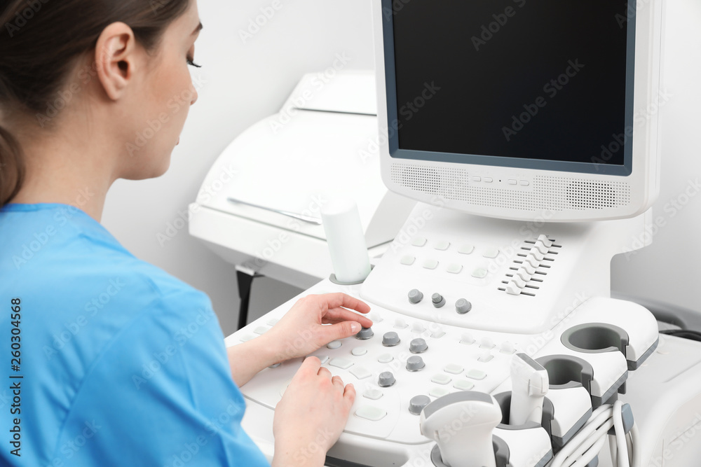 Sonographer operating modern ultrasound machine in clinic Sonographer operating modern ultrasound machine in clinic