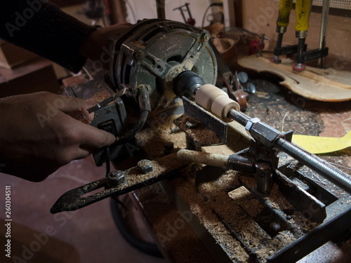 Carpenter working on self made wood lathe with chisel