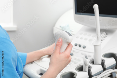 Sonographer operating modern ultrasound machine in clinic, closeup