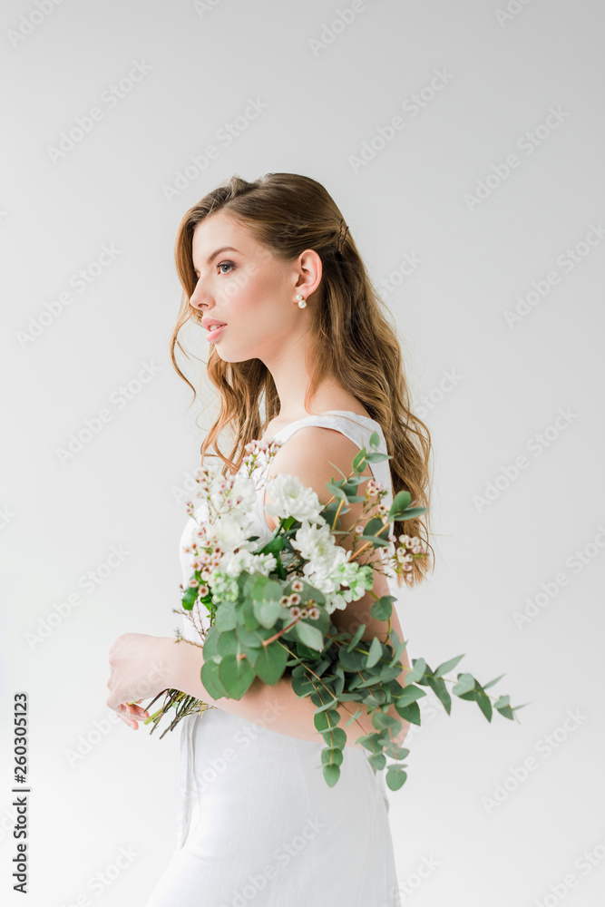 dreamy young woman in dress holding flowers on white