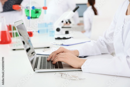 Medical student working with laptop in modern laboratory, closeup
