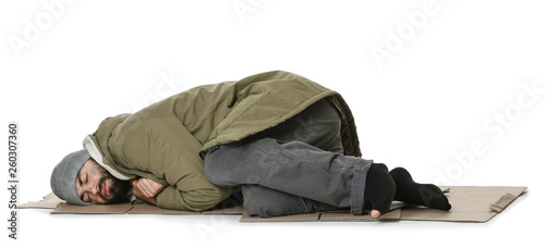 Poor homeless man lying on cardboard, white background photo