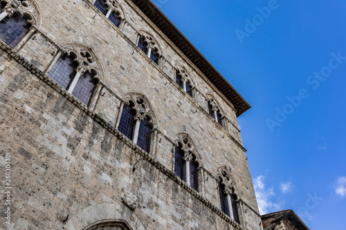 Old Italian ancient building facade on a diagonal bottom composition on a solid blue sky © jordieasy