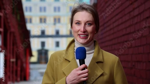 Caucasian female news reporter with microphone reporting news story on street