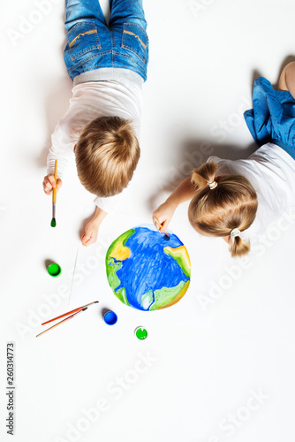 Ecology concept with two prety little kids painting earth on white background photo