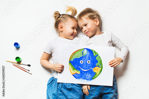 Ecology concept with two prety little kids painting earth on white background photo