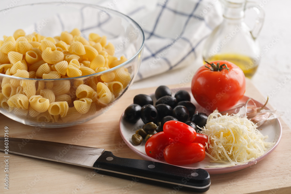 cooking pasta. Ingredients: tomatoes, Parmesan, olives and pasta.