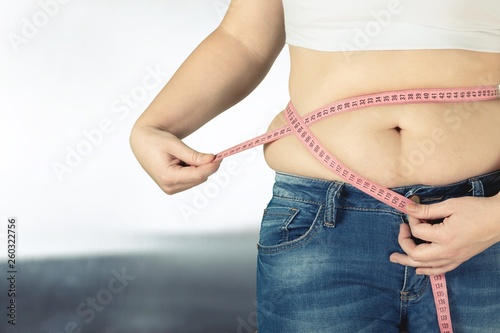Close-up female figure with measuring tape on grey background