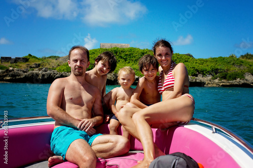 Happy beautiful fashion family, children and parents, dressed in hawaiian shirts, enjoying day trip with speed boat © Tomsickova