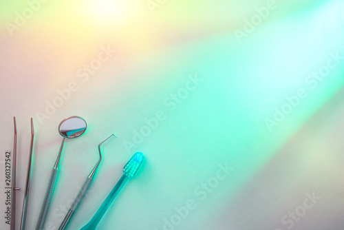 Dentist tools on white table illuminated with green light top