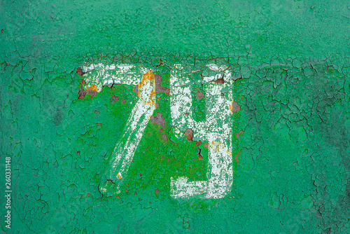 Texture of rusty metal, painted green with white number seventy nine on it. Horizontal texture of cracks and peels paint on rusty steel photo