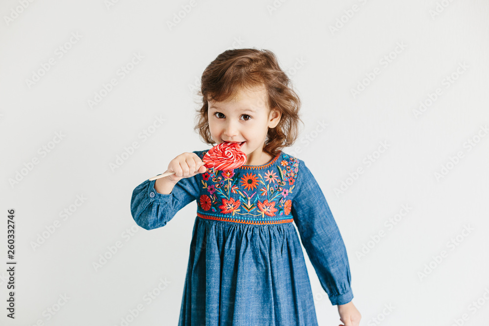 Little girl eating red heart shape lollipops Little girl eating red heart shape lollipops