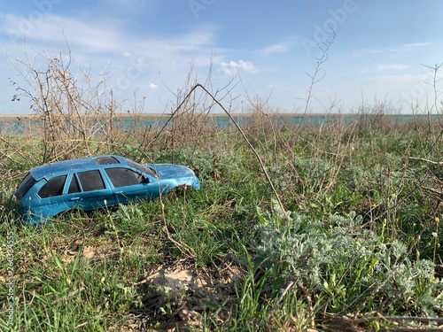 Blue toy car stands in the grass. Outdoor recreation. Green grass texture. Children's toy lying on the ground.