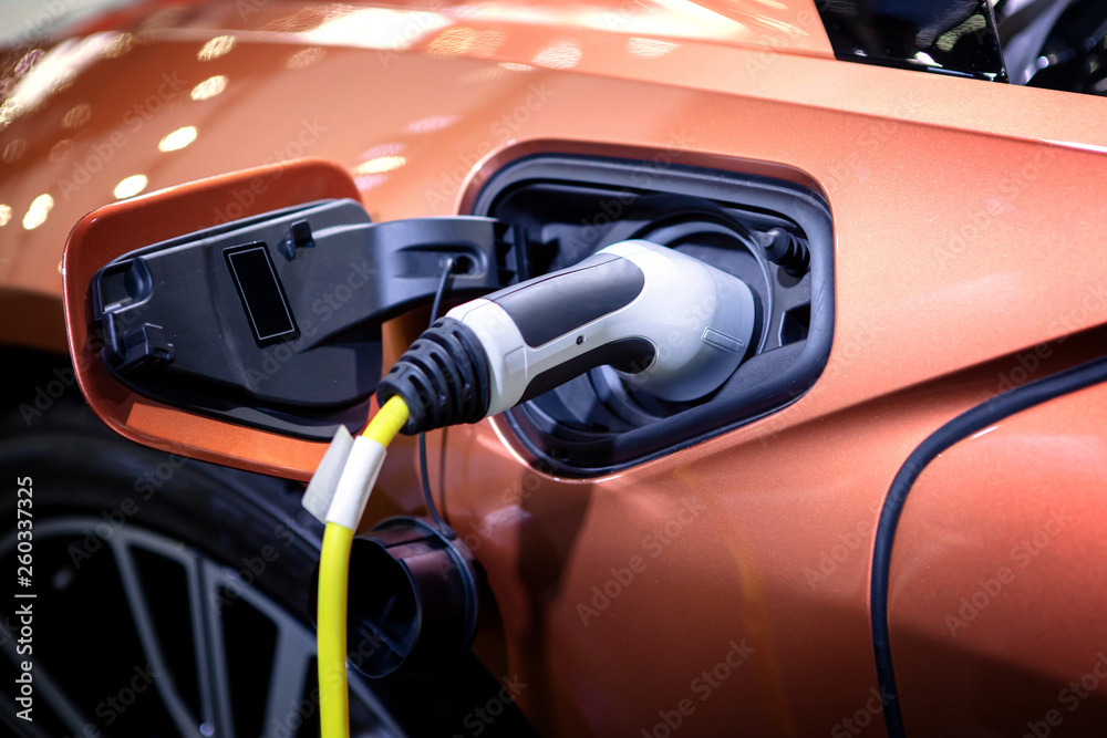 The power supply plugged into an electric car to charging a battery at