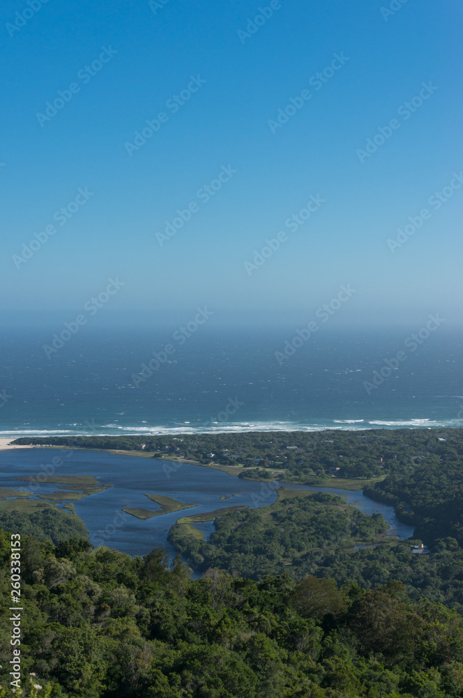 Vast ocean and river mouth lagoon surrounded by forest. Aerial landscape