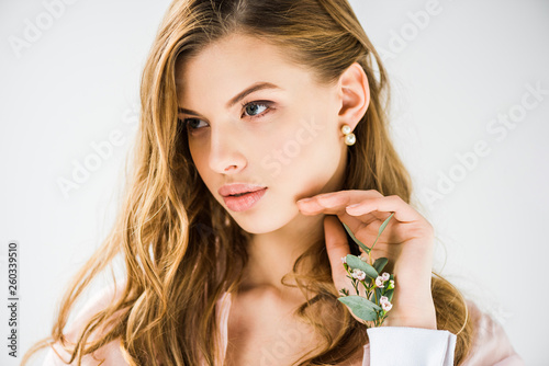 attractive woman with eucalyptus leaves and chamelaucium flowers in hand on white