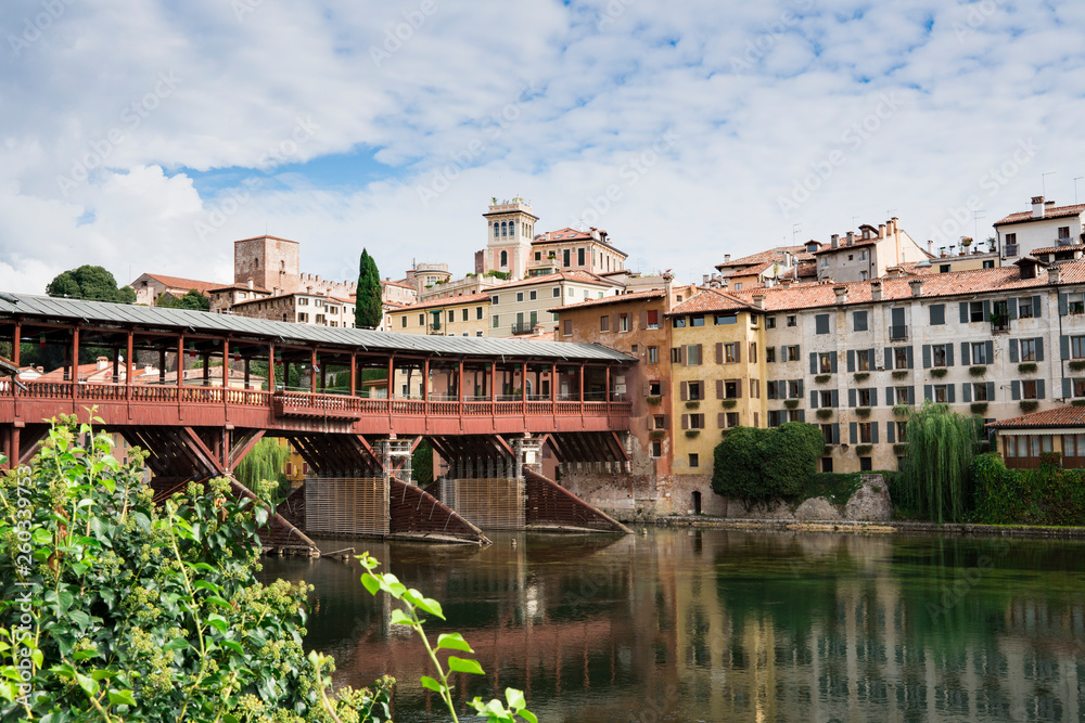 colorful houses  along river Brenta in Bassano del Grappa, Italy. With reflection in water and old wooden bridge