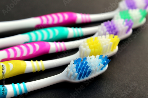 Multi-colored toothbrushes lie on a black background