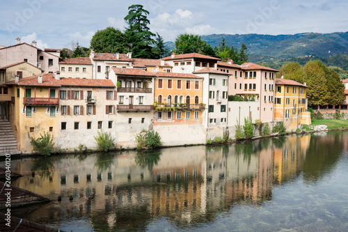 colorful houses along river Brenta in Bassano del Grappa, Italy. With reflection in water