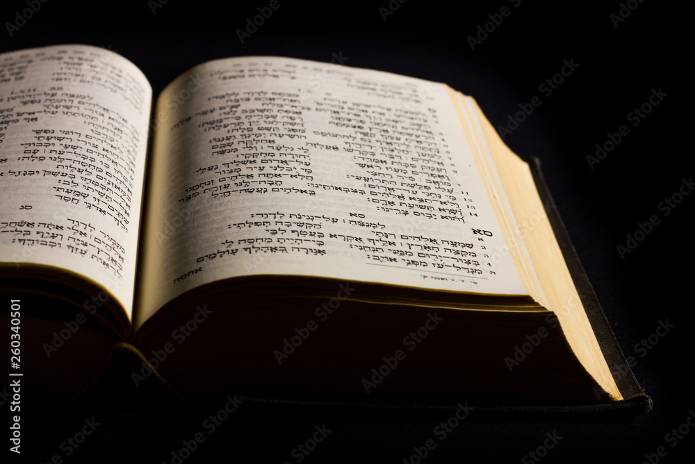 Open hebrew Bible, isolated on black background, with side lighting