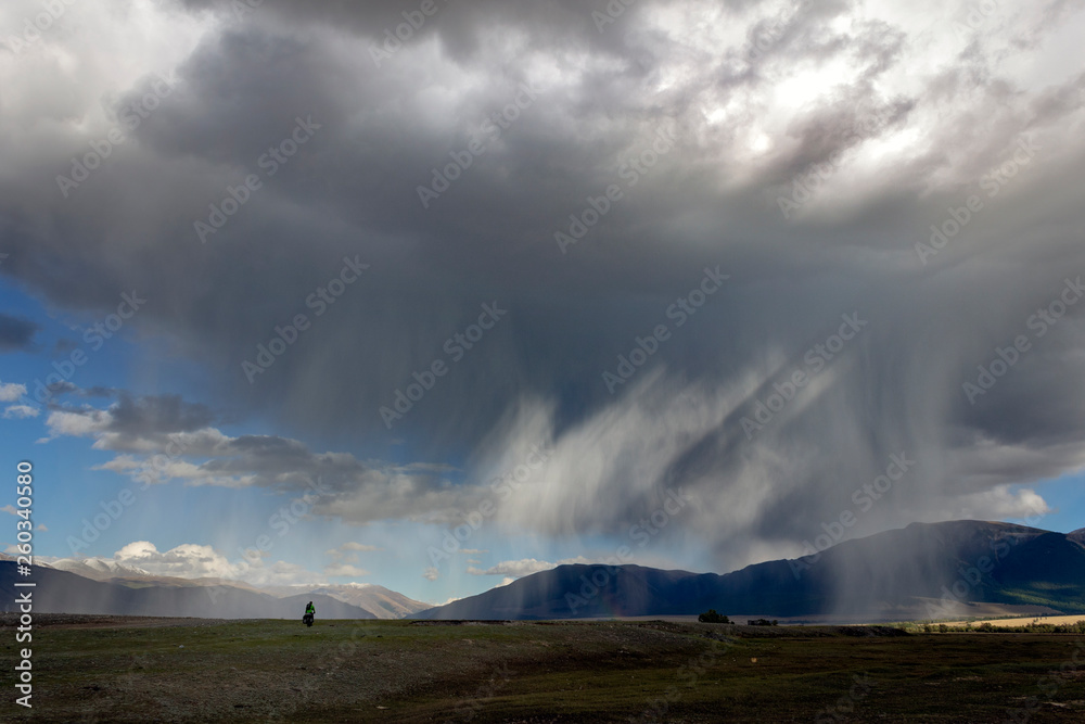 Wide angle view of a thunderstorm with rain shaft and anvil in the mountains