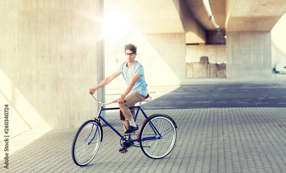Fototapeta premium people, style, leisure and lifestyle - young hipster man riding fixed gear bike on city street