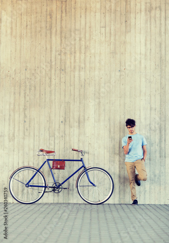 people, communication, technology, leisure and lifestyle - hipster man with smartphone and fixed gear bike on city street