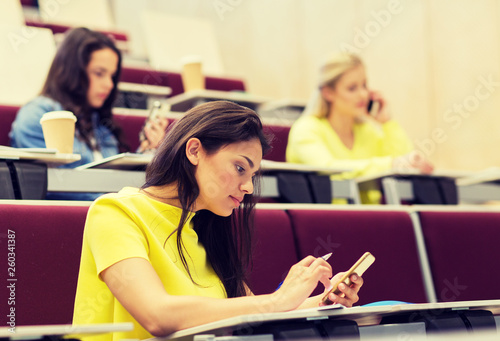 education, high school, university, learning and people concept - student girls with smartphones on lecture © Syda Productions
