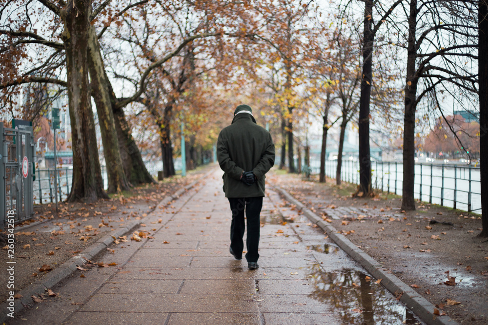 old man walking away,following the path on a rainy autumn day