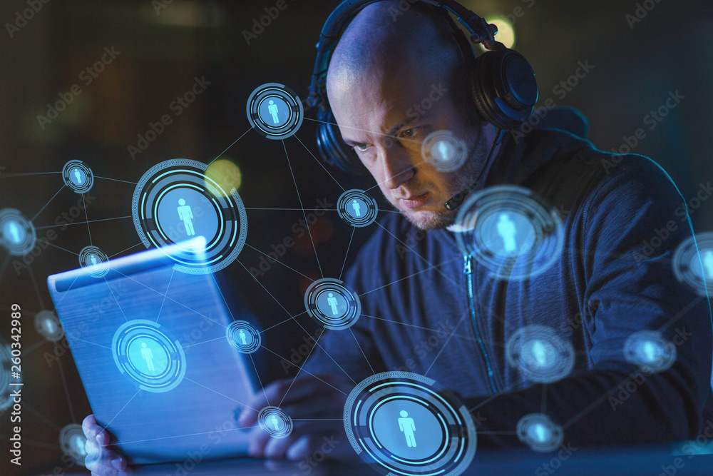 cybercrime, hacking and technology concept - male hacker with headset using laptop computer for cyber attack or wiretapping in dark room cybercrime, hacking and technology concept - male hacker with headset using laptop computer for cyber attack or wiretapping in dark room
