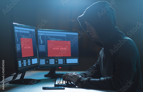 cybercrime, hacking and technology concept - male hacker with access denied message on computer screen using virus program for cyber attack in dark room