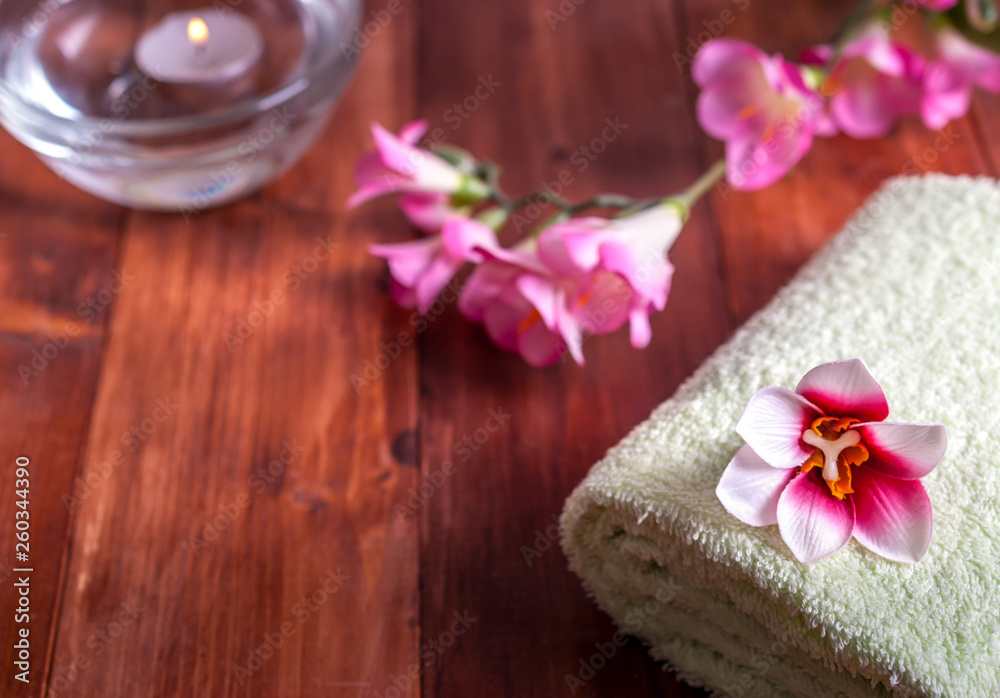 Towel with flowers and a candle on a wooden background