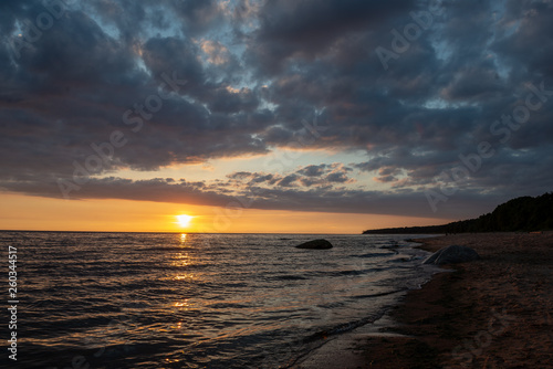 Bilde på lerret colorful sunset over calm sea beach with dark blue water and dramatic contrasty