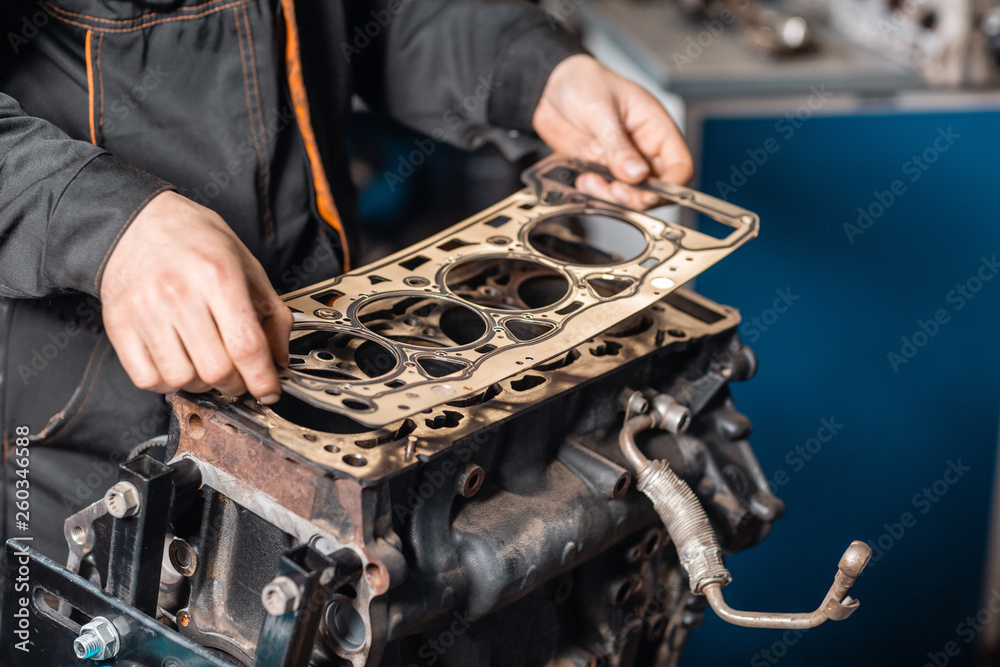 Sealing gasket in hand. The mechanic disassemble block engine vehicle