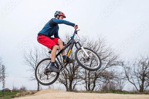 Man on a mountain bike performing a dirt jump.