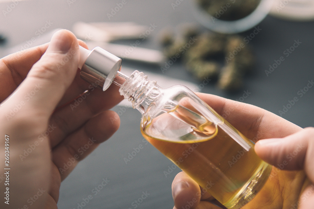 hemp product, Hand holding bottle of Cannabis oil in pipette, close up, natural herb, medical marijuana concept, CBD cannabis OIL. - obrazy, fototapety, plakaty 