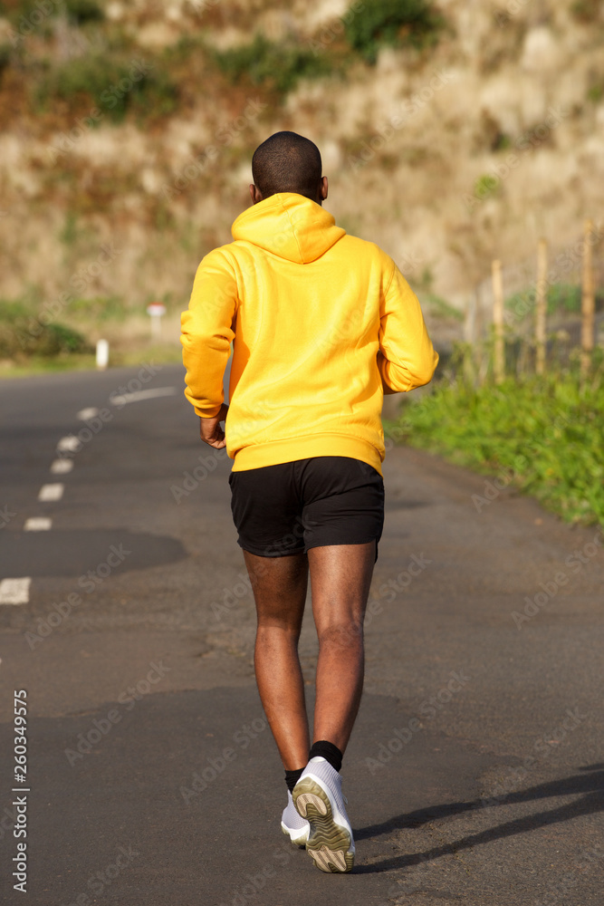 Full body behind of african american sport man running on street Full body behind of african american sport man running on street