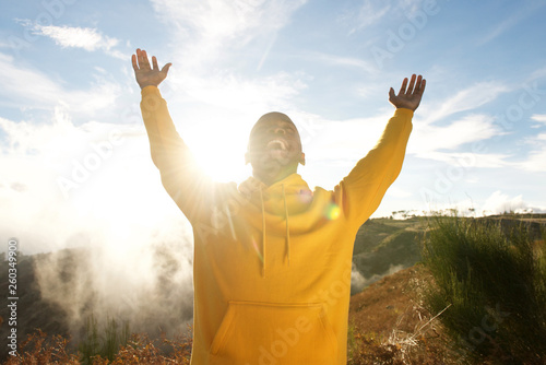 happy young african american man with arms raised in air outdoors © mimagephotos
