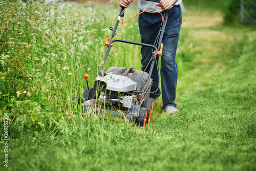 Man is using lawn mower on his countryside yard.